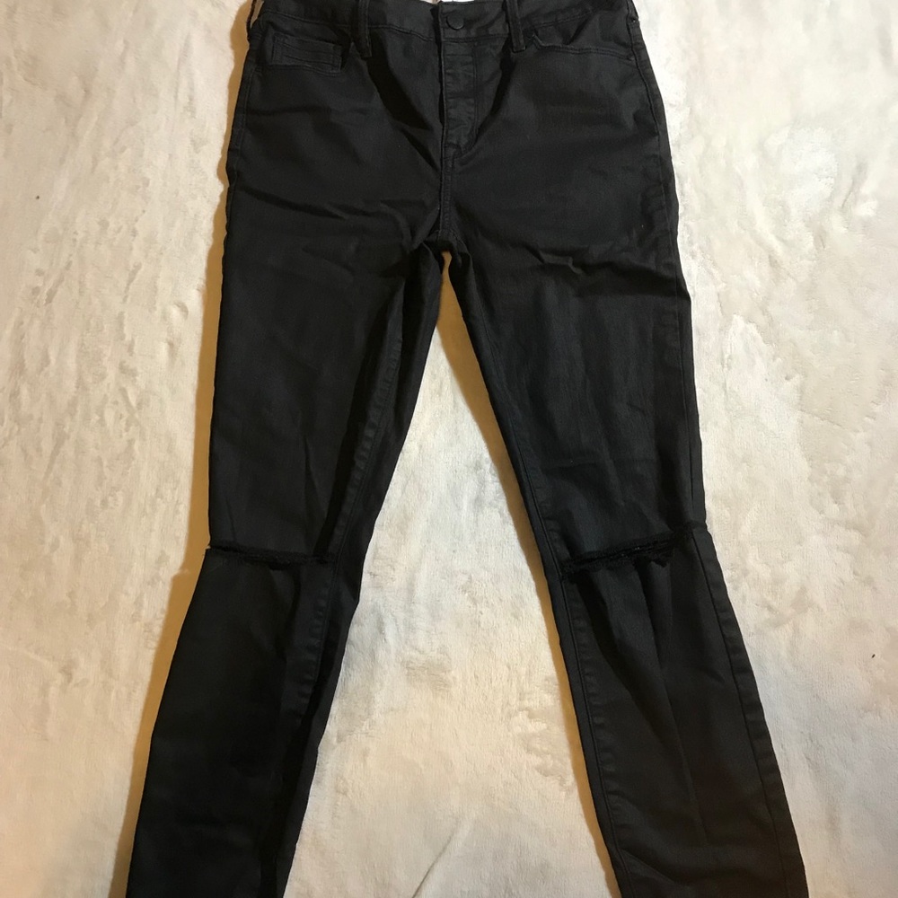 Black pants with distressed holes at the knees.